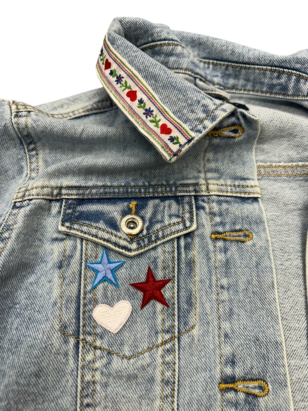 Adams + Hegwood light-wash denim jacket with embroidered collar ribbon, stars, and heart detail on chest pocket.