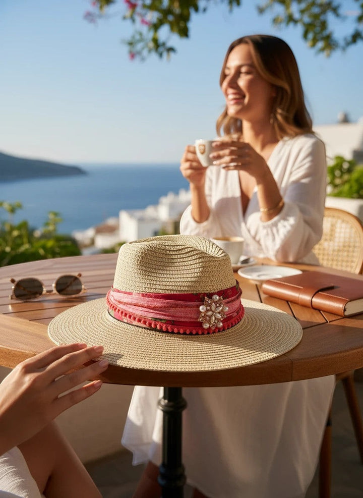 Adams + Hegwood straw fedora hat with pink floral band, pom-pom trim, and pearl brooch. Natural straw.