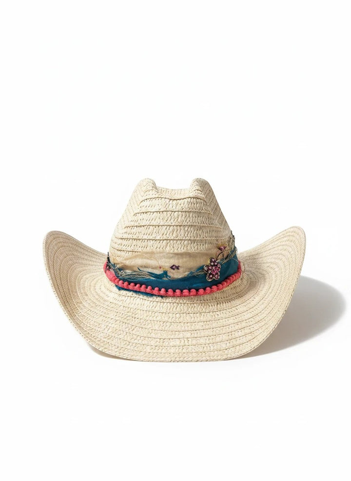 Adams + Hegwood woven straw Western hat with a blue fabric band, pink pom-pom trim, and floral embellishment.