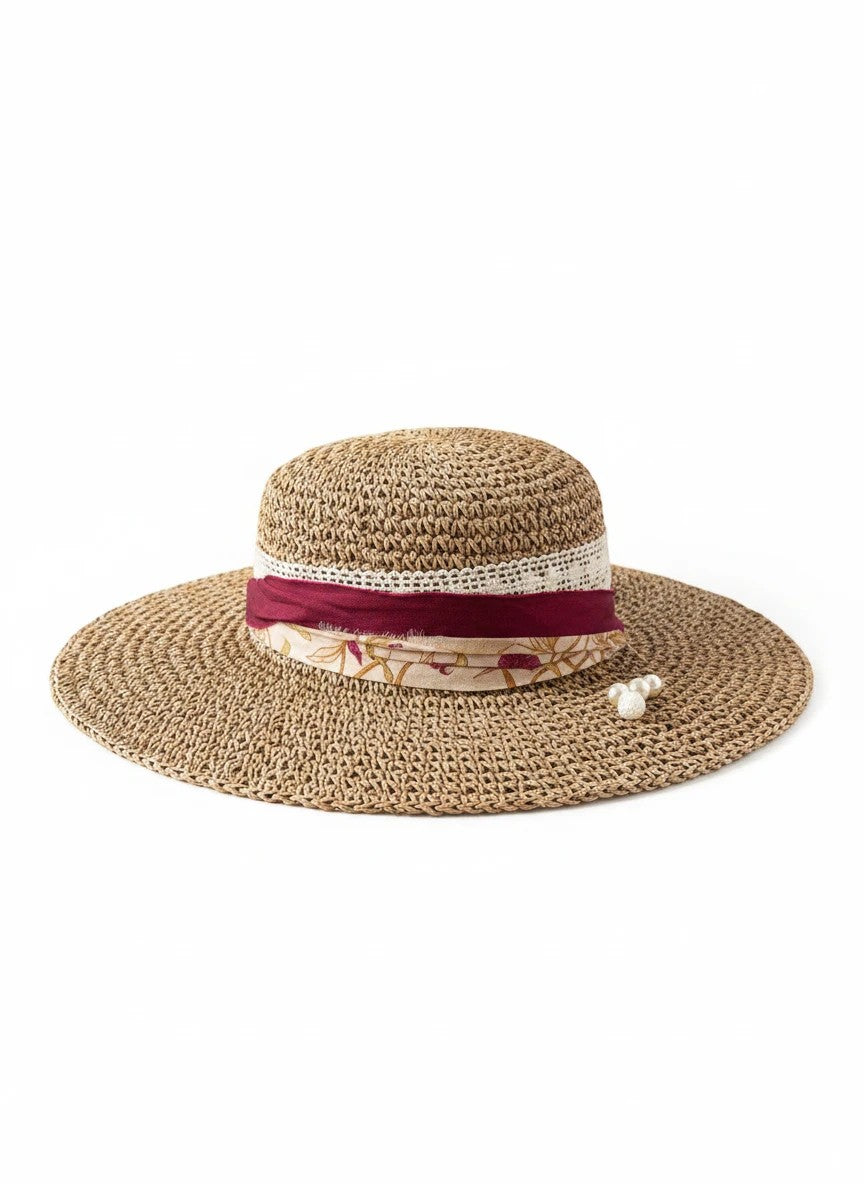 Adams + Hegwood woven straw sun hat with wide brim, decorative burgundy ribbon, floral fabric band, white lace trim, and faux pearl accent.