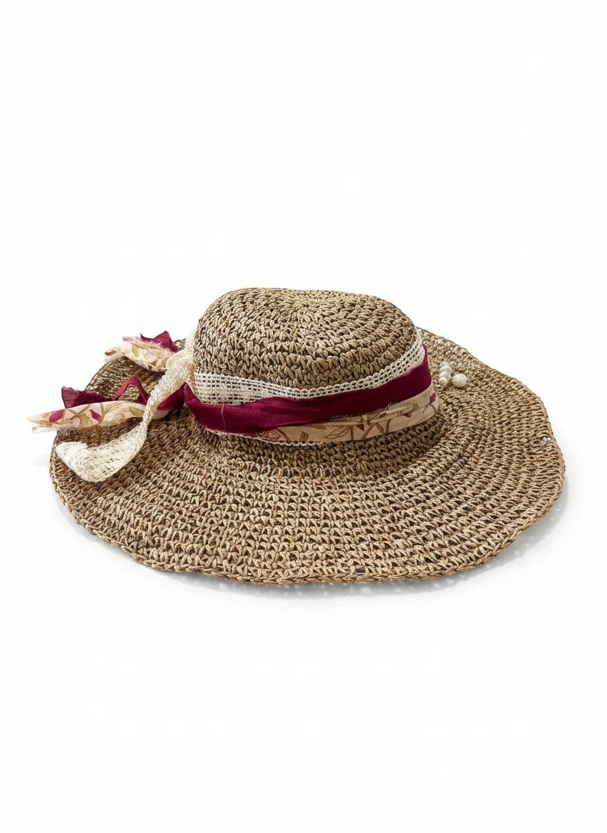 Adams + Hegwood woven straw wide brim sun hat with decorative burgundy ribbon, floral fabric, lace trim, and faux pearls.