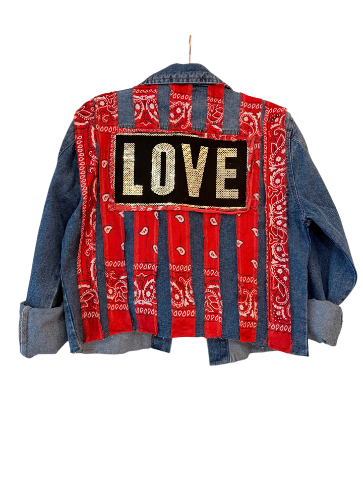 The Denim Muse handmade XL denim jacket on a hanger, back view with red bandana stripes and sequin LOVE patch