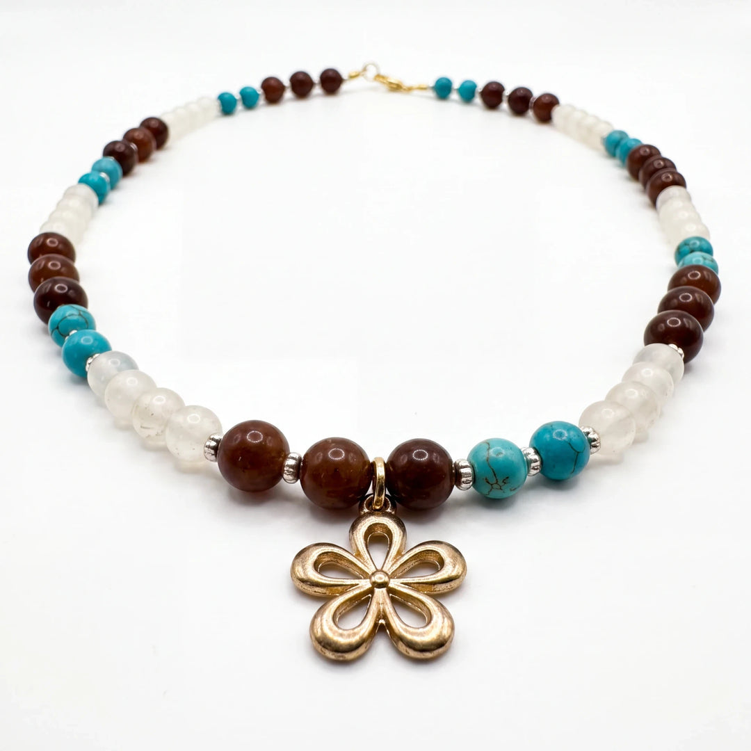 Natalie Adams Hegwood Studio beaded necklace with brown, white, and turquoise beads and a gold-tone flower pendant.