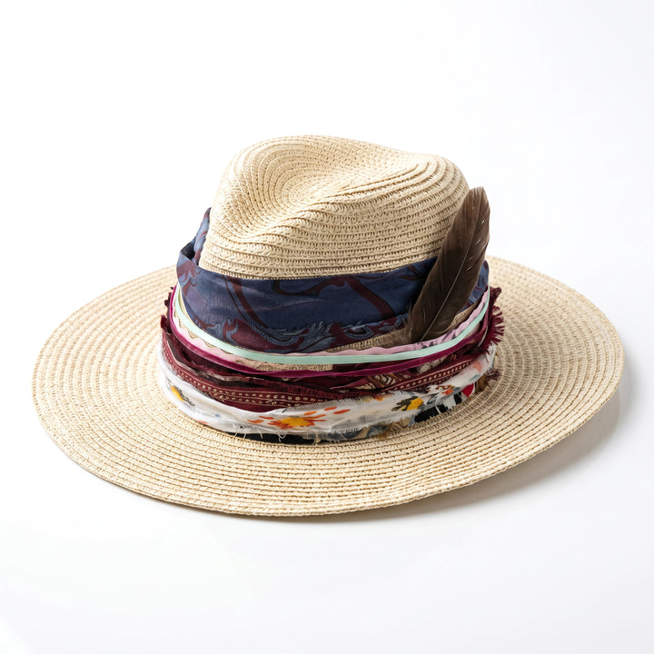 Natalie Adams Hegwood Studio bohemian straw hat with wide brim, layered fabric ribbons, and natural feather accent.