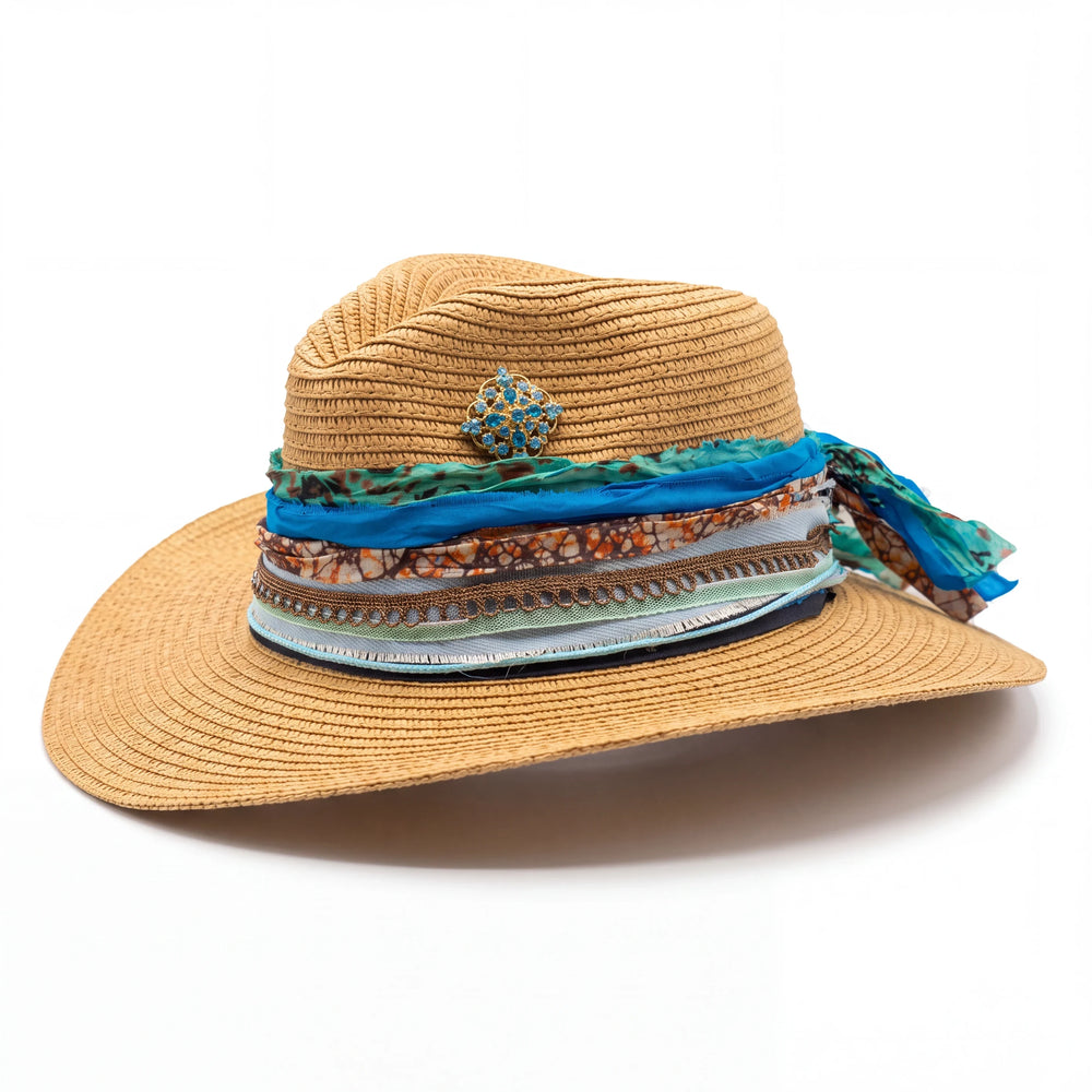 Natalie Adams Hegwood Studio straw fedora with cobalt silk, copper print, and a gold filigree brooch on a wide brim.