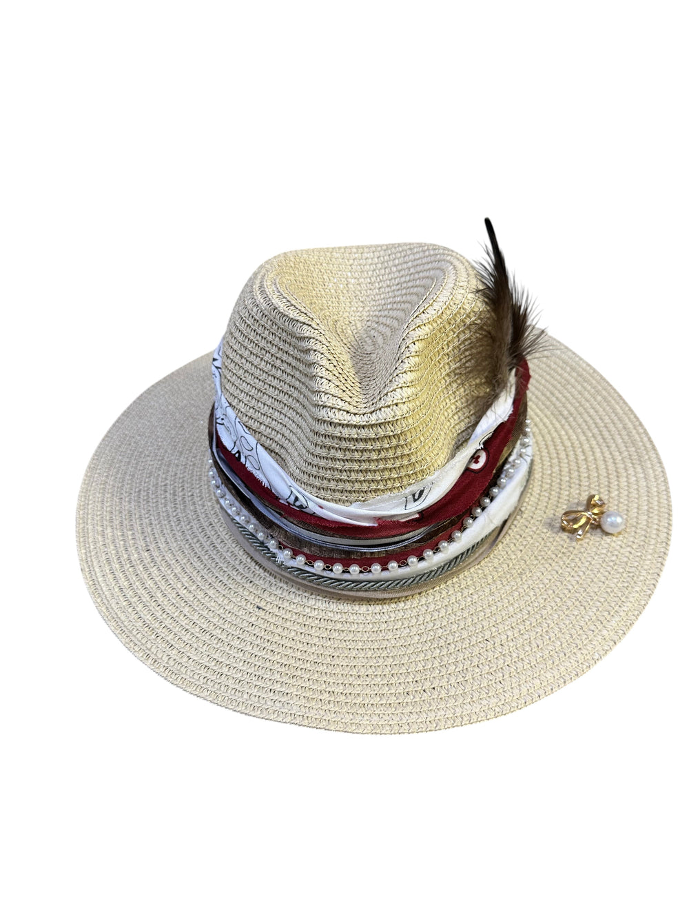 Natalie Adams Hegwood Studio straw fedora with a decorative band featuring pearls, fabric layers, and a feather accent.