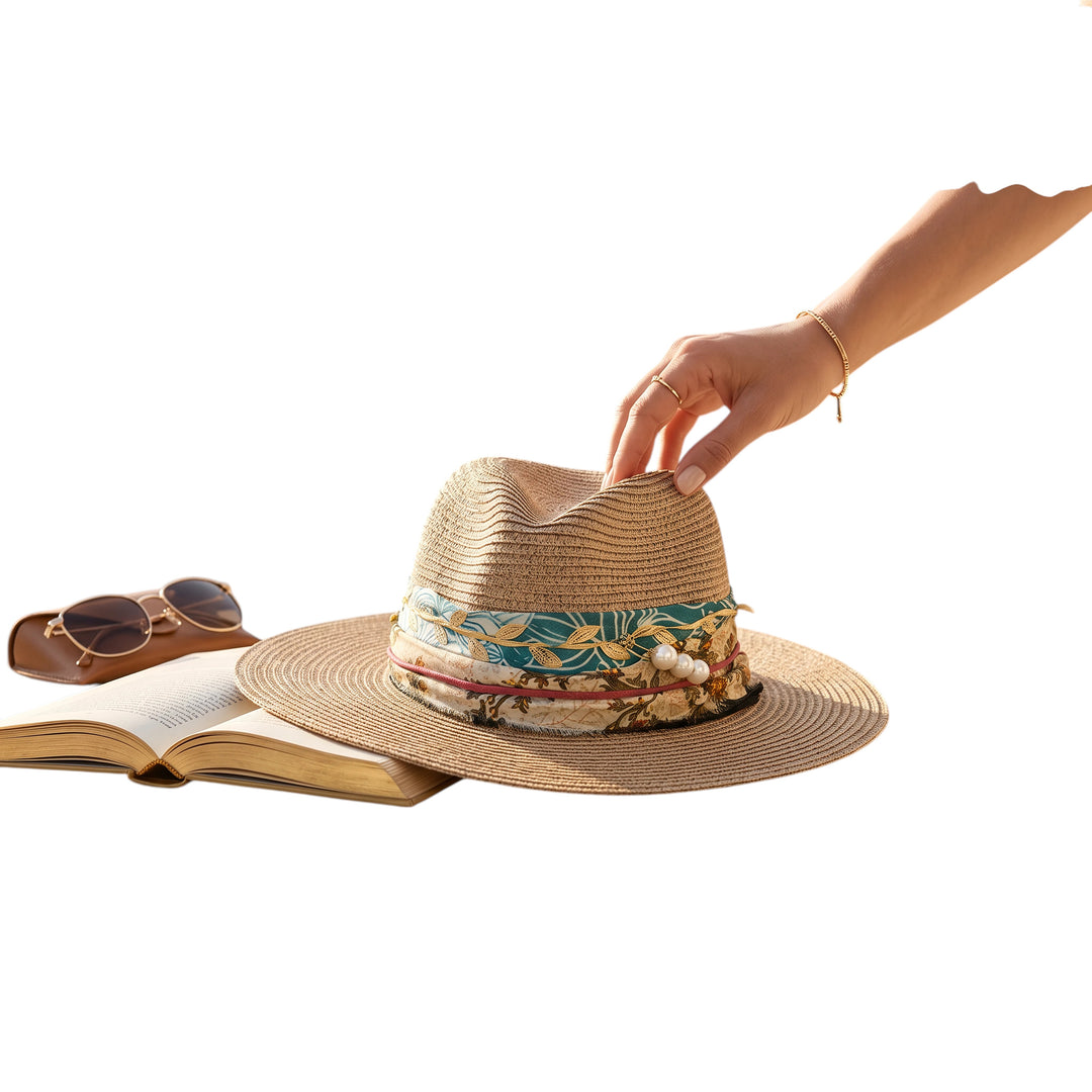 Natalie Adams Hegwood Studio woven straw fedora with a multi-colored leaf print band and pearl accents on a table