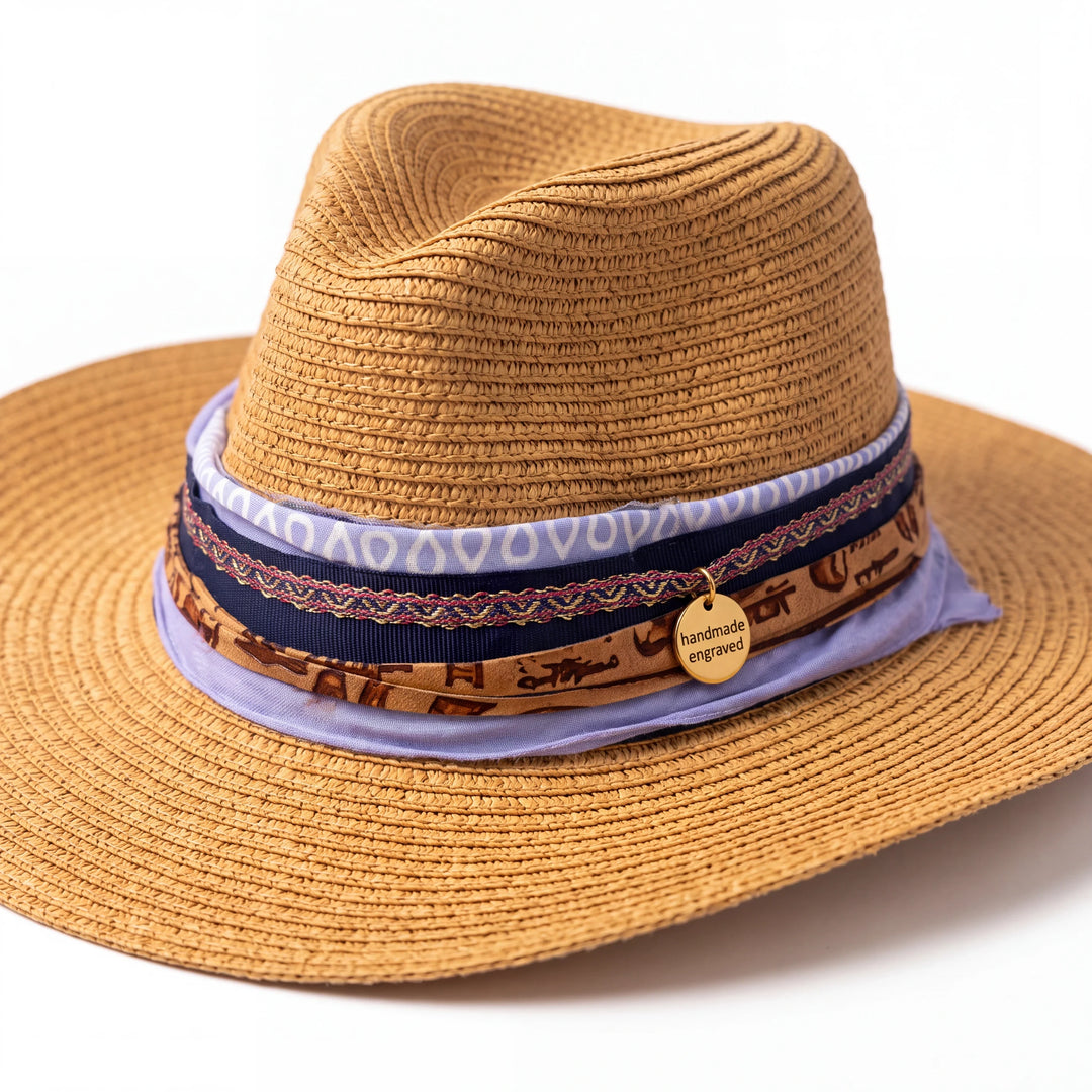Natalie Adams Hegwood Studio hand-embellished tan straw fedora with a lavender, navy, and gold charm hat band.