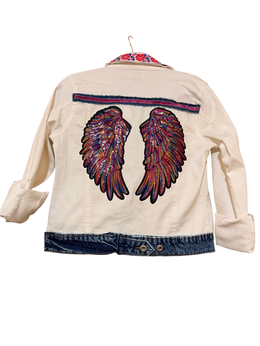 Back of the cream denim jacket with a large sequined angel wings patch in pink, purple and gold.