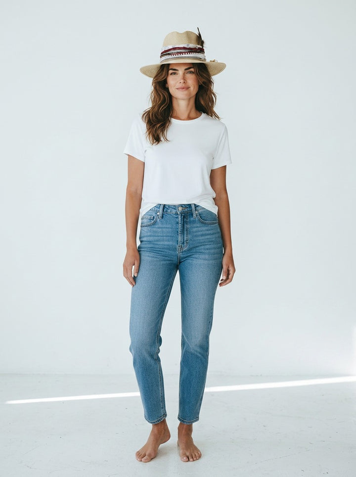 Natalie Adams Hegwood Studio model wearing a white crew neck t-shirt, blue denim jeans, and a decorative straw hat.